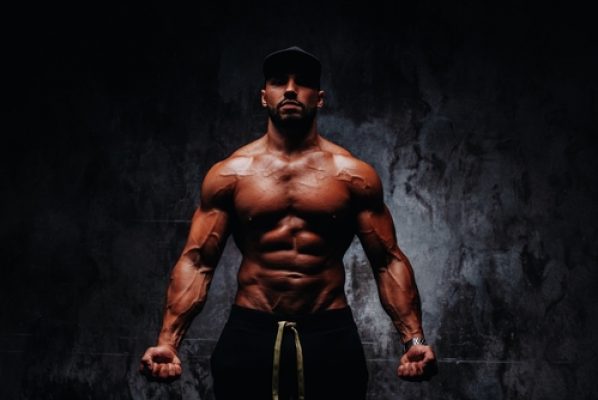 Young,Strong,Man,Bodybuilder,In,Cap,On,Stone,Wall,Background